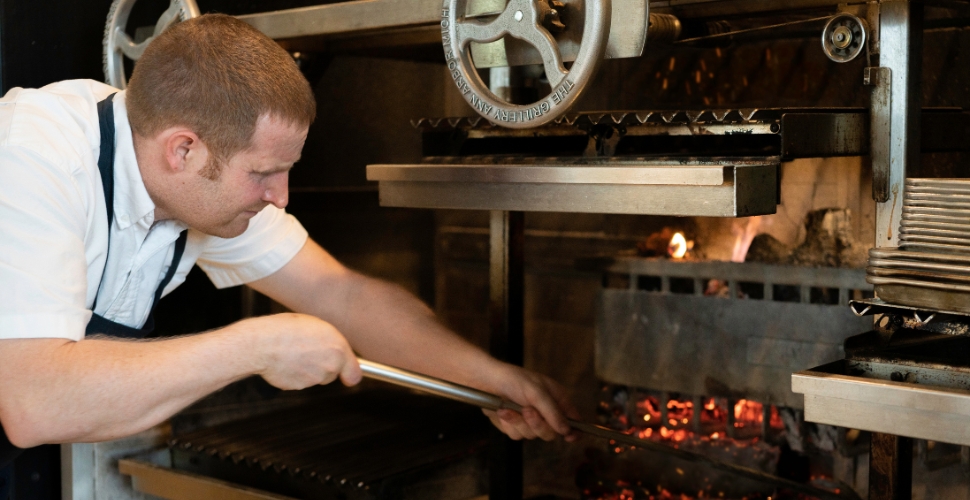 Cedar Creek Winery's Head Chef Neil Taylor stoking the rustic grill at Home Block