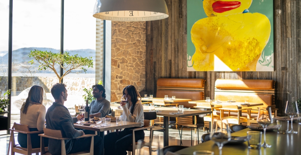 A group dining inside Home Block Restaurant at Cedar Creek in front of the bright open window and elevated homely decor